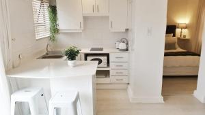 a white kitchen with a sink and a stove at Carrington Cottage in Cape Town
