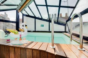 a swimming pool with a swan in a glass house at NOCNOC - Villa Paradis, piscine et rooftop au coeur de Nantes in Nantes