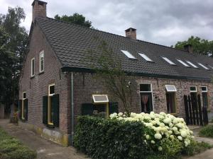 Uma casa de tijolos vermelhos com rosas brancas à frente. em Vakantiehuis In het Voorhuis em Dommelen