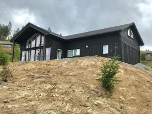 een zwart huis bovenop een heuvel bij Lillebjørn in Trysil