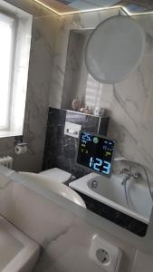 ein Badezimmer mit einer weißen Badewanne, einem Waschbecken und einer Uhr in der Unterkunft Unterkunft A.Lambrecht in Oberhausen