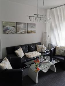 sala de estar con sofá negro y mesa de cristal en Apartments Lindenstraße, en Wilhelmshaven