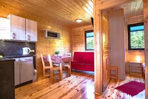 a kitchen and dining room with a table and a red couch at Słoneczna Polana in Mielno