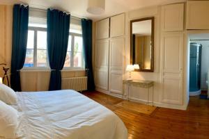 a bedroom with a bed and a mirror and blue curtains at Gîte de Lafleur in Dury