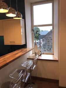 a kitchen with three stools in front of a window at Pineapple Apartments in Aberdeen