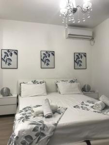 una camera da letto con un grande letto bianco e un lampadario a braccio di Studio Angel stan na dan Novi Sad a Novi Sad