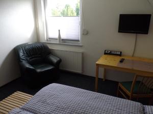 een kamer met een stoel, een bureau en een televisie bij Ferienwohnung Fritzke in Lemförde