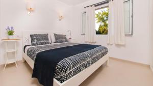 una camera da letto bianca con un letto con lenzuola bianche e nere di Apartamento Pine Beach en Alcudia a Alcudia