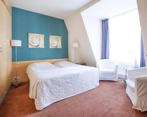 een slaapkamer met een wit bed en een blauwe muur bij Hotel Gevers in Scheveningen