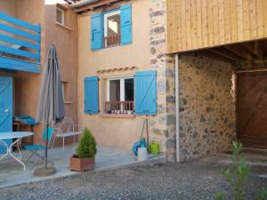 a house with blue doors and a table and an umbrella at La Bergerie in Sost