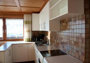 una cocina con armarios blancos y fregadero en Ferien in Feld 109, en Langenegg