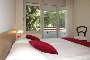 Un dormitorio con una cama con almohadas rojas y una ventana en Exclusive Central Apartment, en Basilea