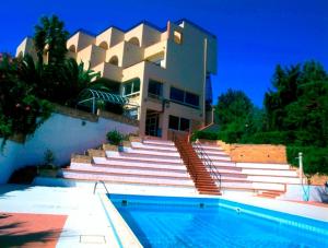 a swimming pool with a balcony and a large building at Helios Hotel in Crotone