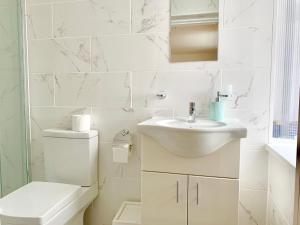 a white bathroom with a sink and a toilet at London Apartments, Close To Station in Ilford