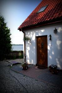 um edifício branco com uma porta de madeira e um banco em Dom pod Skrzydłami em Gawliki Wielkie