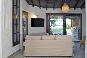 a living room with a white couch and a tv at Γεράνι Suite in Ktima Gerostathi in Polykhrono