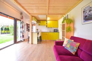 een woonkamer met een paarse bank en een keuken bij Happy Place - Casuta Galbena in Domneşti
