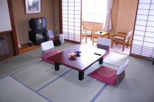 Akakura Wakui Hotel في ميوكو: غرفة معيشة مع طاولة وكراسي وتلفزيون