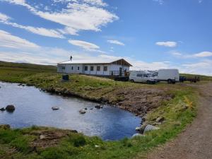 Una casa con dos camiones estacionados junto a un río. en Bjarnastaðir Guesthouse, en Kópasker