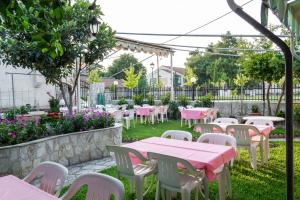 een patio met roze tafels, witte stoelen en bloemen bij Finikas in Larisa