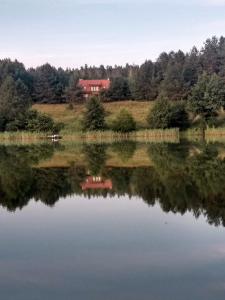 un reflejo de una casa roja en un lago en Za piecem en Guzowy Piec