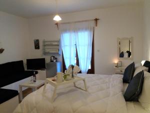 a bedroom with a large white bed and a living room at Anofli Suites in Skopelos Town