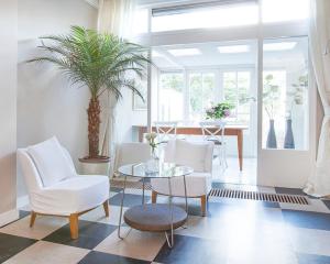 ein Wohnzimmer mit einem Tisch und weißen Stühlen in der Unterkunft Hotel Gevers in Scheveningen