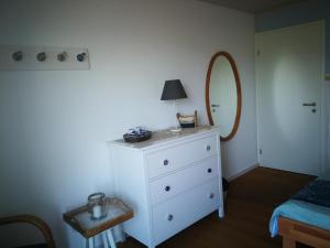 a bedroom with a white dresser and a mirror at B&B Whitianga in Vinelz
