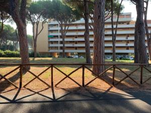 a fence in a park with trees and a building at Appartamenti Pian d'Alma in Punta Ala