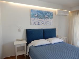 a bedroom with a blue bed and a painting on the wall at Cielo mini suita in Karteros