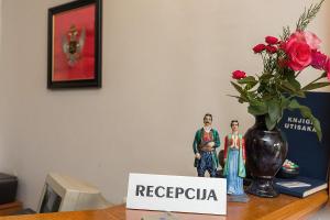 two dolls are standing next to a vase with flowers at Hotel Dominus in Bijelo Polje