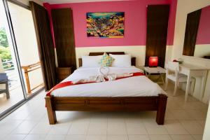 a bedroom with a bed with a pink wall at OK Phuket in Kata Beach