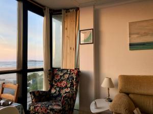 ein Wohnzimmer mit einem Stuhl und einem großen Fenster in der Unterkunft Somo Playa Vistas in Somo