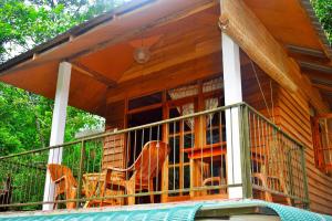 un porche cubierto de una cabaña de madera con sillas en Ella Green Cottages en Ella