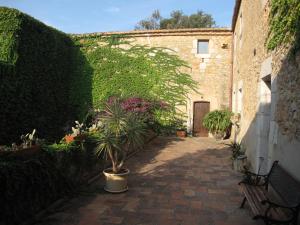 un callejón con plantas, un edificio y un banco en Mas de San Feliu, en Viladamat