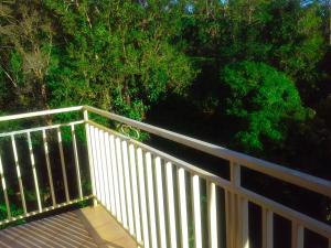 a wooden deck with a white railing and trees at chez Manu in Le Robert