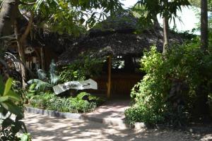 a small hut with a thatched roof in a garden at Triniti Oysterbay in Dar es Salaam