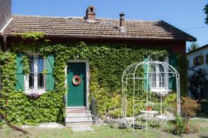 une petite maison avec une porte verte et du lierre dans l'établissement Il Cottage, à Vigevano