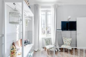 sala de estar blanca con 2 sillas y TV en Il Cottage, en Vigevano