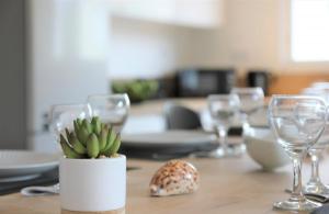 a table with wine glasses and a potted plant on it at Cap Coz Cottage 4* a 500 m de la plage de sable fin in Fouesnant