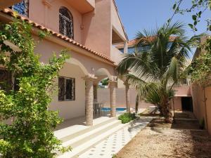 une maison avec un palmier à côté d'une piscine dans l'établissement Villa Savana, à Saly Portudal