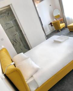 a large bed in a room with a yellow chair at Widegate Residential in London