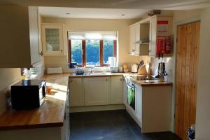 a kitchen with white cabinets and a sink and a window at Honey Cottage in Amlwch