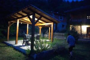 a person walking under a wooden pavilion in a yard at Hotel Rural Llerau in Taranes