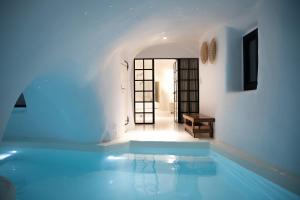 una grande piscina in una stanza bianca con di Aleria Luxury Cave Santorini a Éxo Goniá