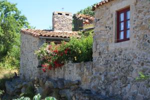 an old stone house with flowers on a wall at Casa de l Bárrio in Picote