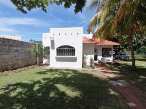 a white house with a palm tree in the yard at La Ceja Beach House in El Tamarindo