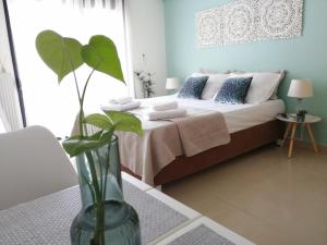 ein Schlafzimmer mit einem Bett mit einer Vase mit einer Pflanze in der Unterkunft City Center Fresh Studio #Self Check In# in Thessaloniki