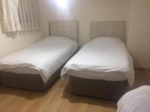 two beds in a small room with white sheets at Çatı Apartment in Istanbul