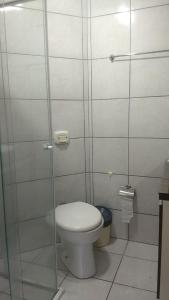 a bathroom with a toilet and a glass shower stall at Apartamento Borges in Itapema +10 photos